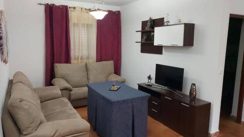 ein Wohnzimmer mit einem Sofa, einem TV und einem Tisch in der Unterkunft Casa del Poniente in Lepe