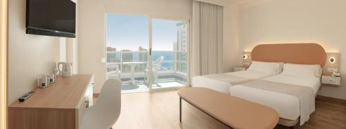 ベニドルムにあるHotel RH Victoria & Spaのベッドと大きな窓が備わるホテルルームです。