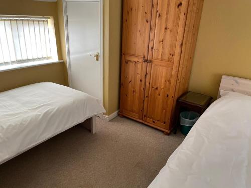 a bedroom with two beds and a cabinet and a window at Sweetpea Cottage in Louth in Louth