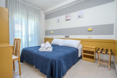 a bedroom with a blue bed with towels on it at Hotel Villa Lina in Riccione