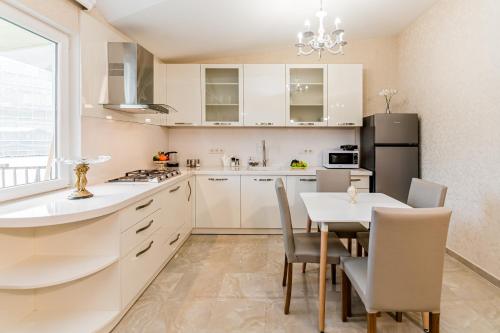 a kitchen with white cabinets and a table with chairs at Dat Exx Apartments On Liberty Square in Tbilisi City
