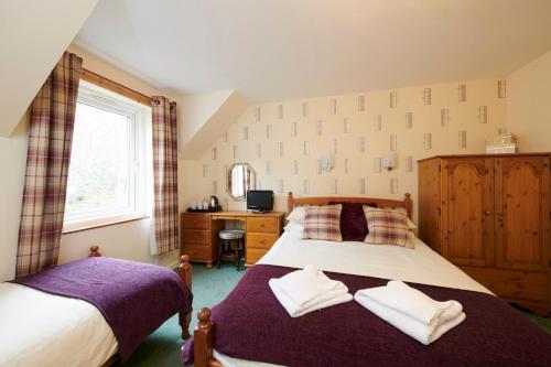 a bedroom with a bed and a desk and a window at Tailrace Inn in Kinlochleven