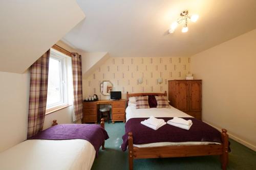 1 dormitorio con 2 camas y escritorio en Tailrace Inn en Kinlochleven