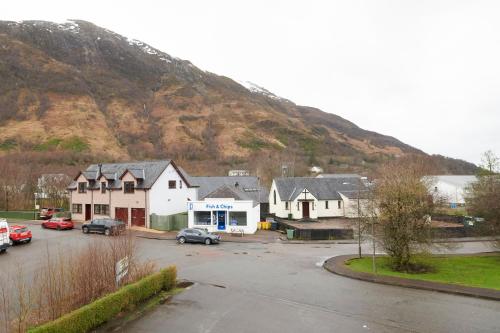 a group of houses in a parking lot next to a mountain at Tailrace Inn in Kinlochleven