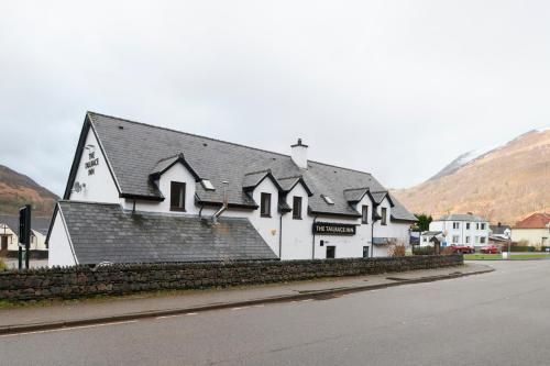 Un edificio blanco con techo negro en una calle. en Tailrace Inn, en Kinlochleven