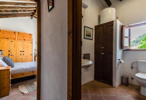 ein Bad mit WC und ein Bett in einem Zimmer in der Unterkunft Casa Mundo - 16th century traditional white village house with pool in Pinos del Valle