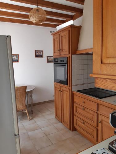 une cuisine avec des armoires en bois et un four à plaques de cuisson dans l'établissement Grand gîte dans son écrin de Nature, à Saint-Laurent-du-Mottay