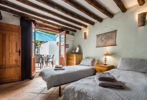 ein Schlafzimmer mit zwei Betten und einem Tisch und Stühlen in der Unterkunft Casa Mundo - 16th century traditional white village house with pool in Pinos del Valle
