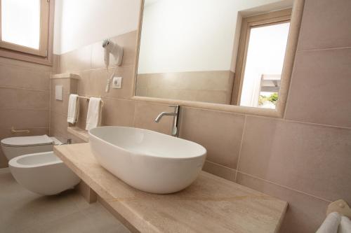 a bathroom with a sink and a toilet and a mirror at La Corte Di Pulicinu in Baja Sardinia