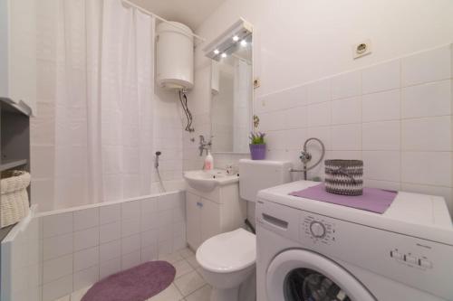 een witte badkamer met een toilet en een wasmachine bij Strawberry in Split