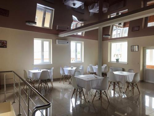 uma sala de jantar com mesas e cadeiras brancas e janelas em Bloom Hotel em Carcóvia