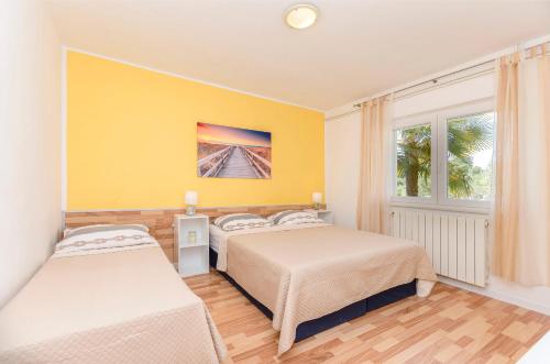 1 dormitorio con 2 camas y pared amarilla en Apartments Ante, en Vodice