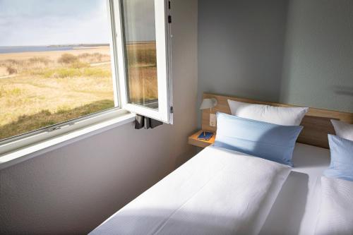 a bedroom with a white bed and a window at TUI BLUE Sylt in Rantum