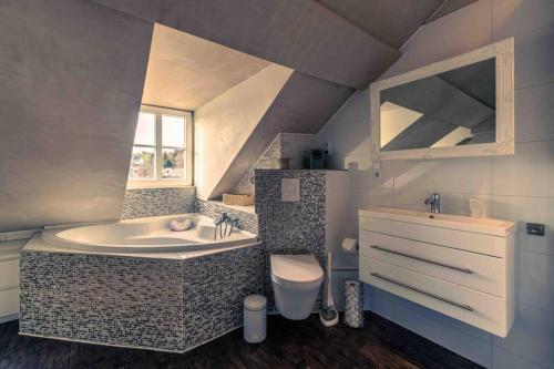 a bathroom with a tub and a toilet and a sink at Altes Schwesternhaus - Homesite Apartments in Weibern