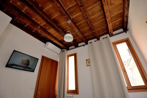 um quarto com cortinas brancas e um tecto de madeira em Casa dea corte apartment em Veneza