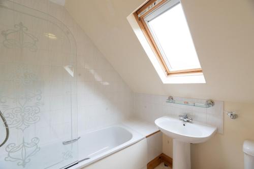 baño con lavabo, bañera y ventana en Capercaillie Cottage en Crianlarich