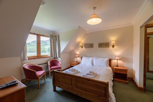 a bedroom with a bed and a desk and chairs at Capercaillie Cottage in Crianlarich