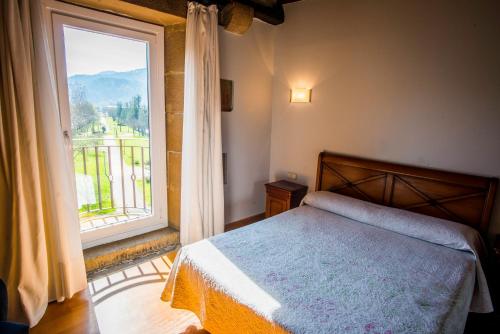 a bedroom with a bed and a large window at Hotel Palacio Atxega in Usúrbil