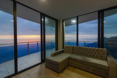 a living room with a couch and large windows at Panorama Kvariati in Kvariati