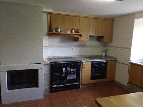 uma cozinha com electrodomésticos pretos e armários de madeira em Casa Malvina em La Coruña
