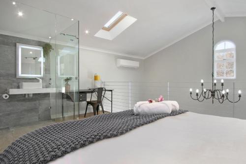 1 dormitorio con 1 cama con lámpara de araña y escritorio en Magnolia Cottage en Ciudad del Cabo