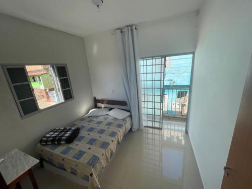 a small bedroom with a bed and two windows at Casa do Disco Voador in São Thomé das Letras