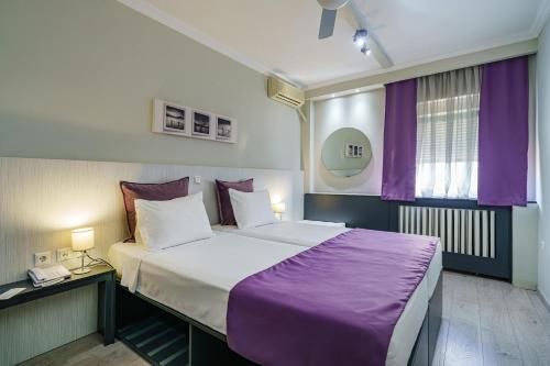 a bedroom with a large bed with purple sheets at Capsis Hotel Thessaloniki in Thessaloniki