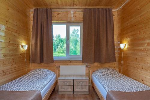 a bedroom with two beds and a window and a chair at Karumetsa Apartment in Otepää
