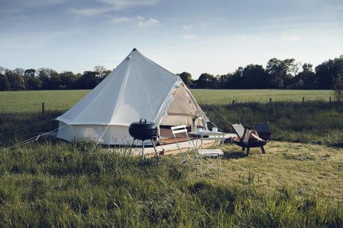 a white tent in a field with some chairs at Home Farm Glamping in Elstree