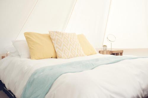 a bed with white sheets and pillows in a room at Home Farm Glamping in Elstree