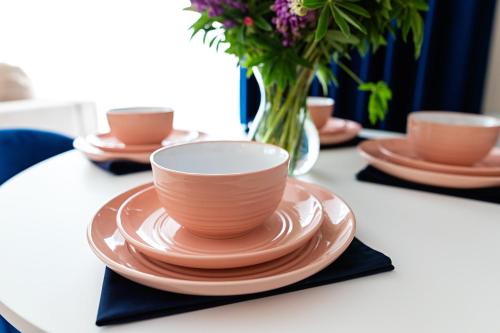 a table with a cup and plates and a vase with flowers at Apartament Bella Rosa z podziemnym parkingiem in Kielce