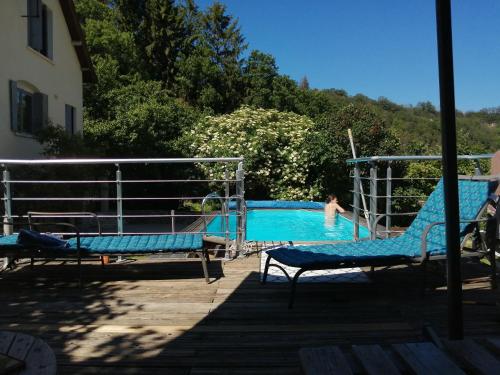 a pool with two chairs and a person in the water at Les bois d'ormes in Bessey-en-Chaume