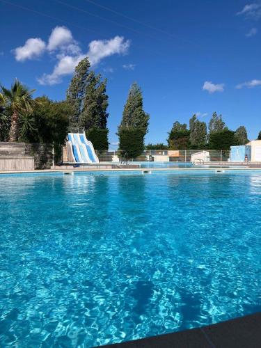une grande piscine d'eau bleue avec toboggan dans l'établissement Mobil-Home Cosy Climatisé 3 chambres, à Vic-la-Gardiole