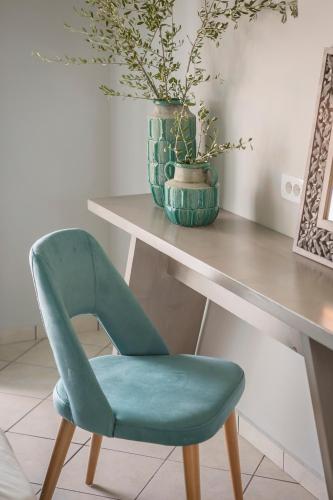 a green chair sitting next to a desk with a vase at Makis Hotel in Skala Kefalonias