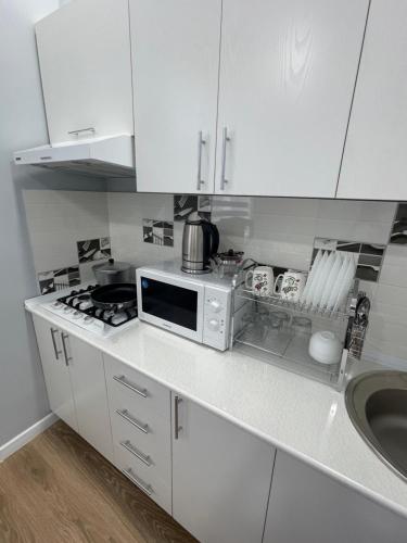 Una cocina blanca con microondas y fregadero. en Amir Temur Apartment in center After renovation, en Tashkent