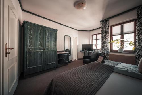 a bedroom with a bed and a chair and a desk at Sommers Hotel Altes Posteck in Reichenbach im Vogtland