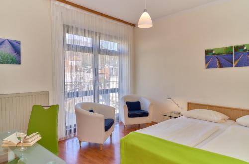 a bedroom with a bed and two chairs and a window at Hotel Garni am Goetheplatz in Bad Münster am Stein-Ebernburg