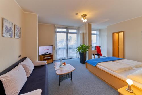 a bedroom with a bed and a couch and a tv at Hotel Garni am Goetheplatz in Bad Münster am Stein-Ebernburg