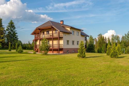 une grande maison sur un champ verdoyant avec des arbres dans l'établissement Karumetsa Apartment, à Otepää