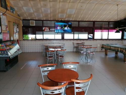 ein Restaurant mit Tischen und Stühlen sowie einem TV in der Unterkunft Alojamentos Martinho in Quintas