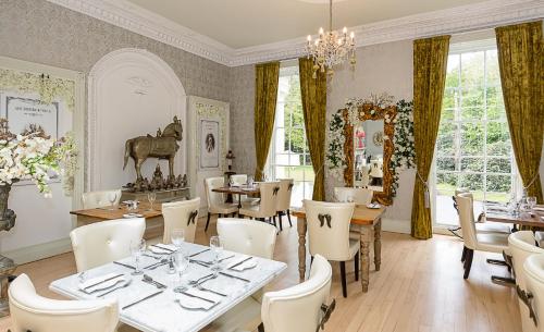 a restaurant with tables and chairs and a chandelier at RainHill Hall Hotel in Rainhull