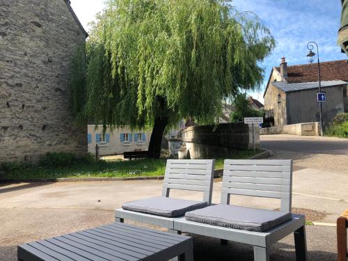 two white chairs and a bench in front of a tree at Auberge du Renard'eau in Bèze