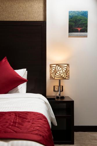 a bedroom with a bed and a lamp on a night stand at Horizon Hotel in Al Başrah