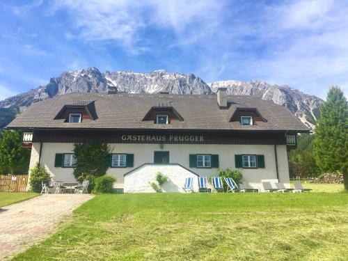 a building with chairs and mountains in the background at Gästehaus Prugger by Schladmingurlaub in Ramsau am Dachstein
