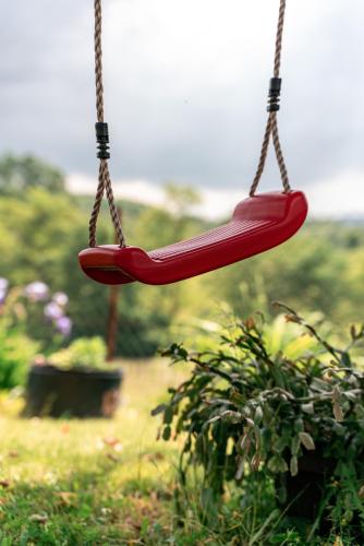 a red swing hanging from a chain in a garden at JELA Countryside House in Kosjerić