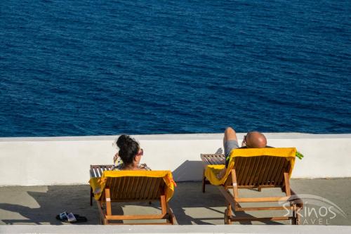 Dos personas sentadas en sillas de jardín en la playa en Alopronoia Sea Breeze en Síkinos