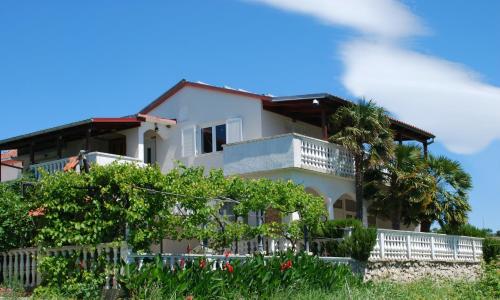 a white house with a balcony and trees at Villa Sabina - Apartments Kroatien in Ražanac