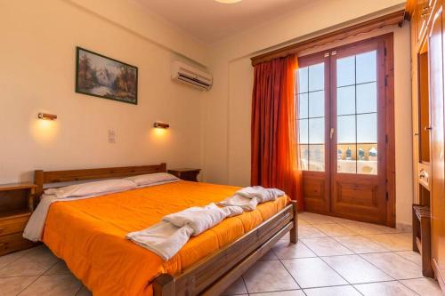 a bedroom with a bed and a large window at Kapetanios Apartments in Agios Stefanos