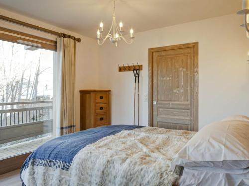 1 dormitorio con cama, ventana y lámpara de araña en Appartement La Tania, 5 pièces, 12 personnes - FR-1-513-17 en La Tania
