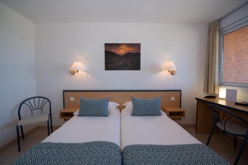 Pokój hotelowy z łóżkiem, biurkiem i krzesłami w obiekcie Hotel Les Galets w mieście Saint-Florent